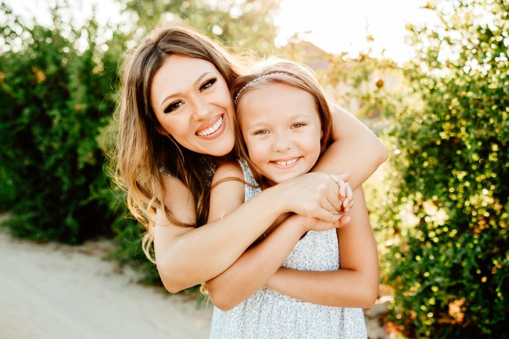 Backlit colorful image of moom embracing her daughter from behind