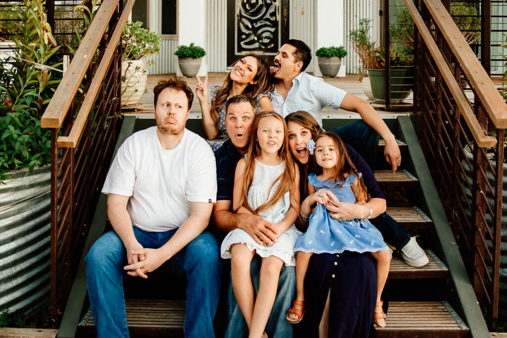 Extended family photo of everyone on a porch making silly faces