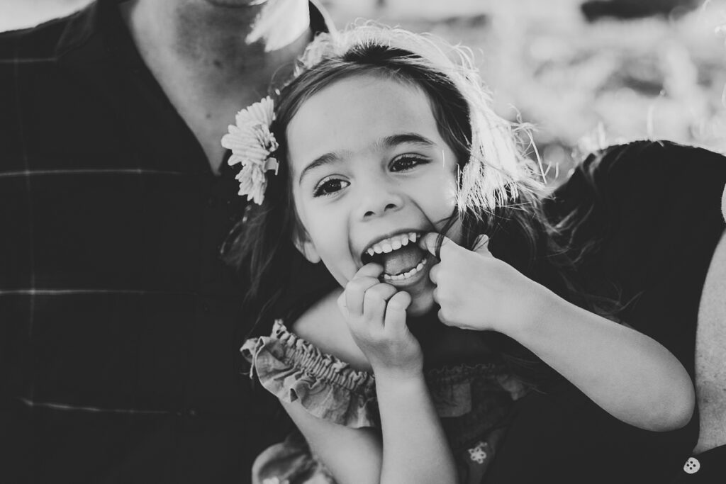 up-close black and white image of a little girl laughing for blog post about importance of hiring a professional photographer.
