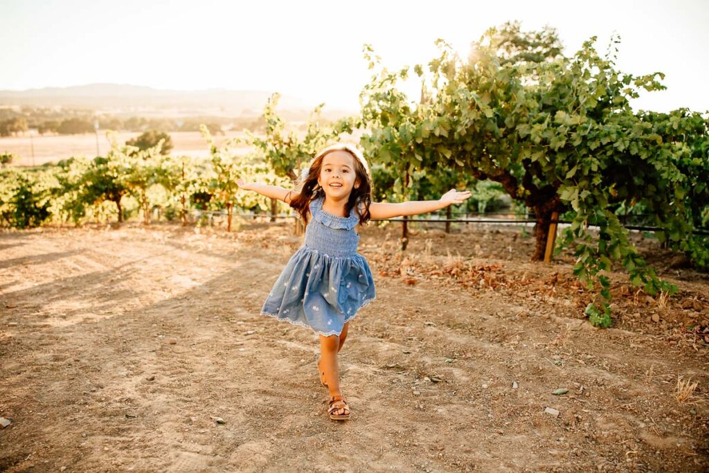 little girl running through a vineyard