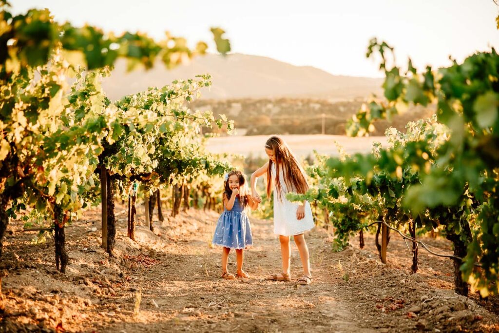 2 young girls in a vineyard for a blog post importance of hiring a family photographer