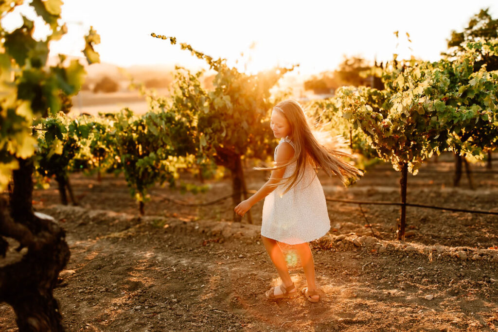 backlit image of girl twirling in a vineyard