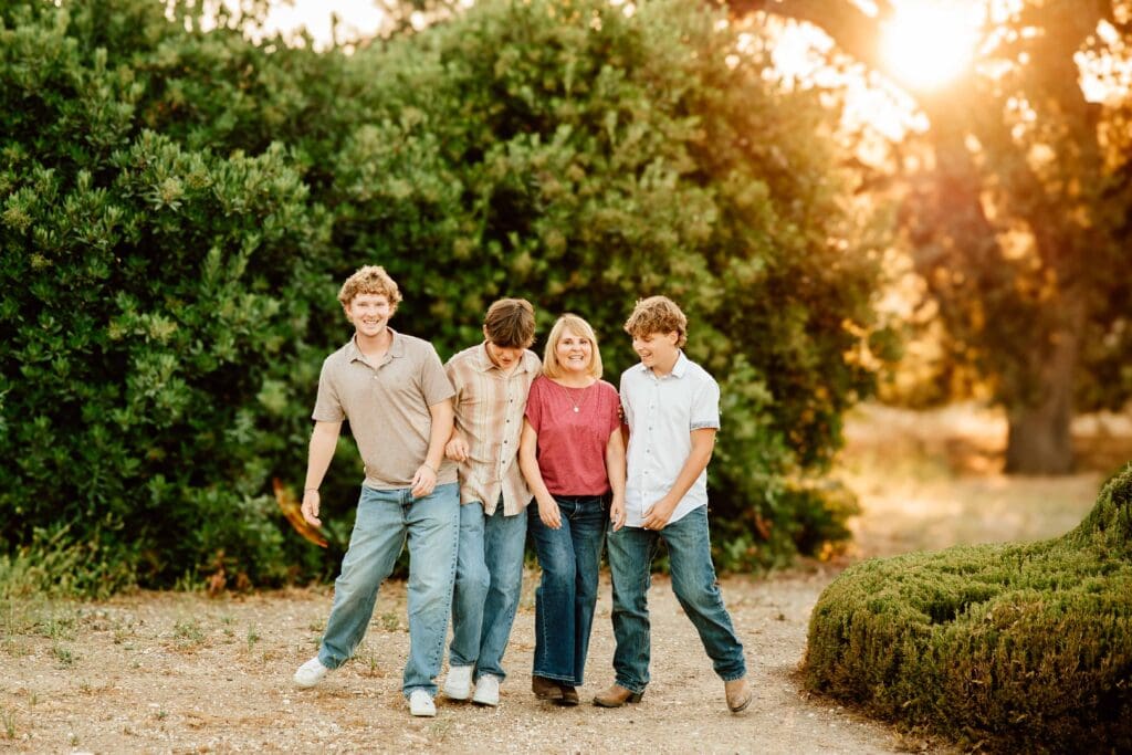 mom and her 3 sons walking and laughing for a blog post about the importance of family photos with older kids