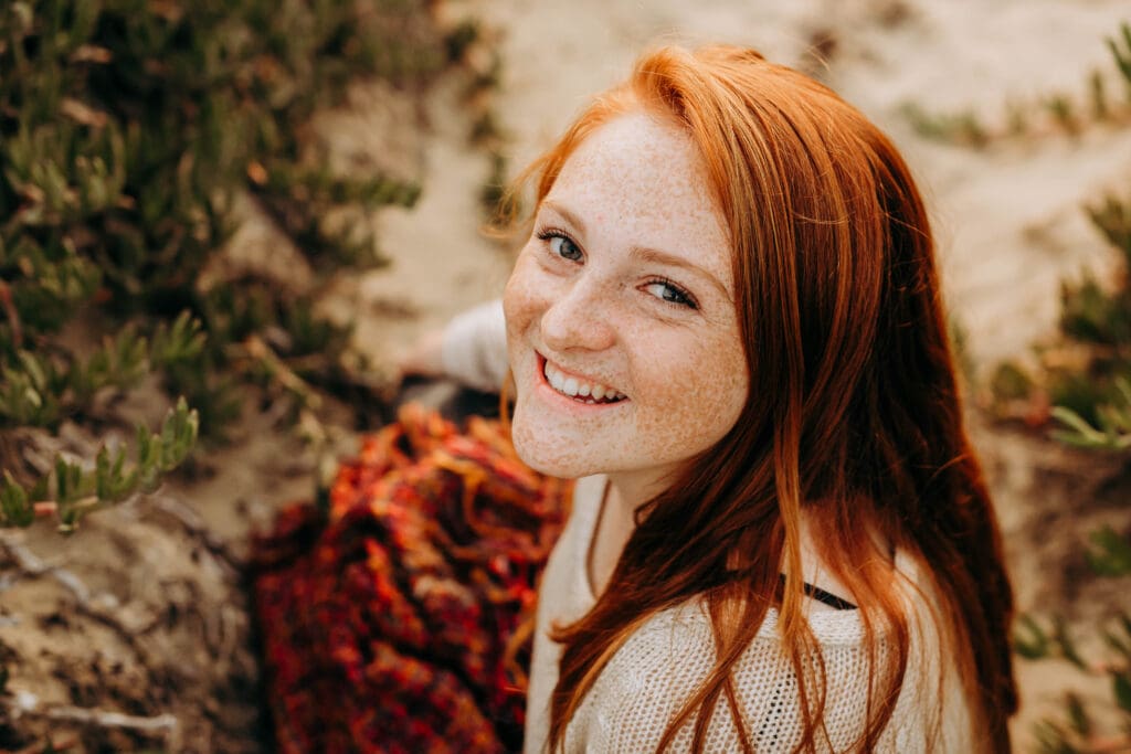 Close up senior portrait of a freckled redhead girl on the beach