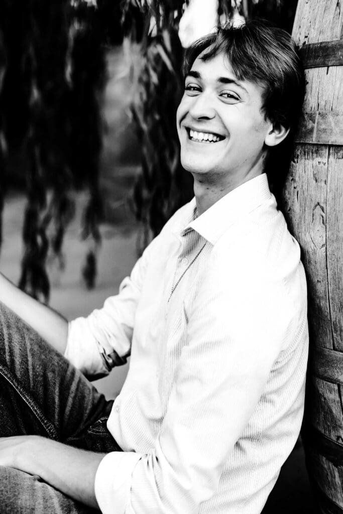 black and white portrait of a senior boy smiling for his high school yearbook photos. 