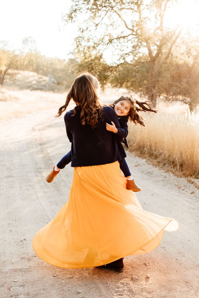 Backlit image of a mom spinning her daughter for a blog post about Family photo session