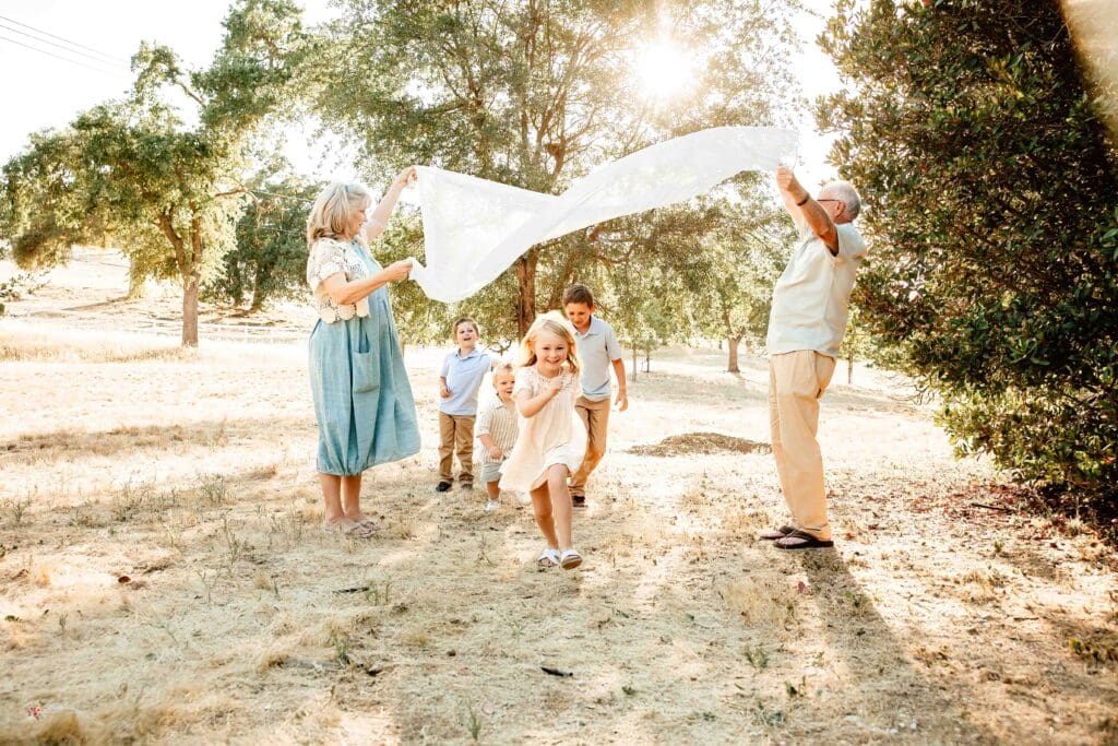 Sunlit image of kids having fun running under a blanket