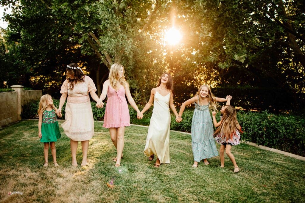 backlit image of 6 cousins holding hands and laughing
