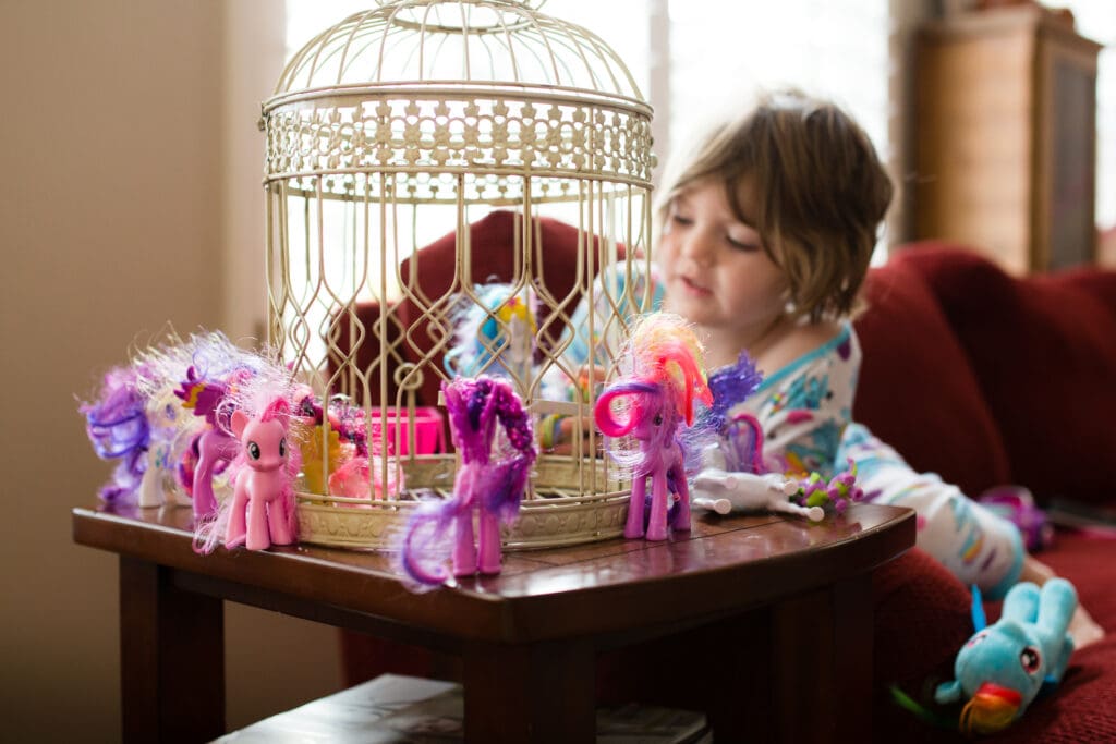 colorful image of toddler girl surrounded by my little poines for a blog post about in-home lifestyle photo session