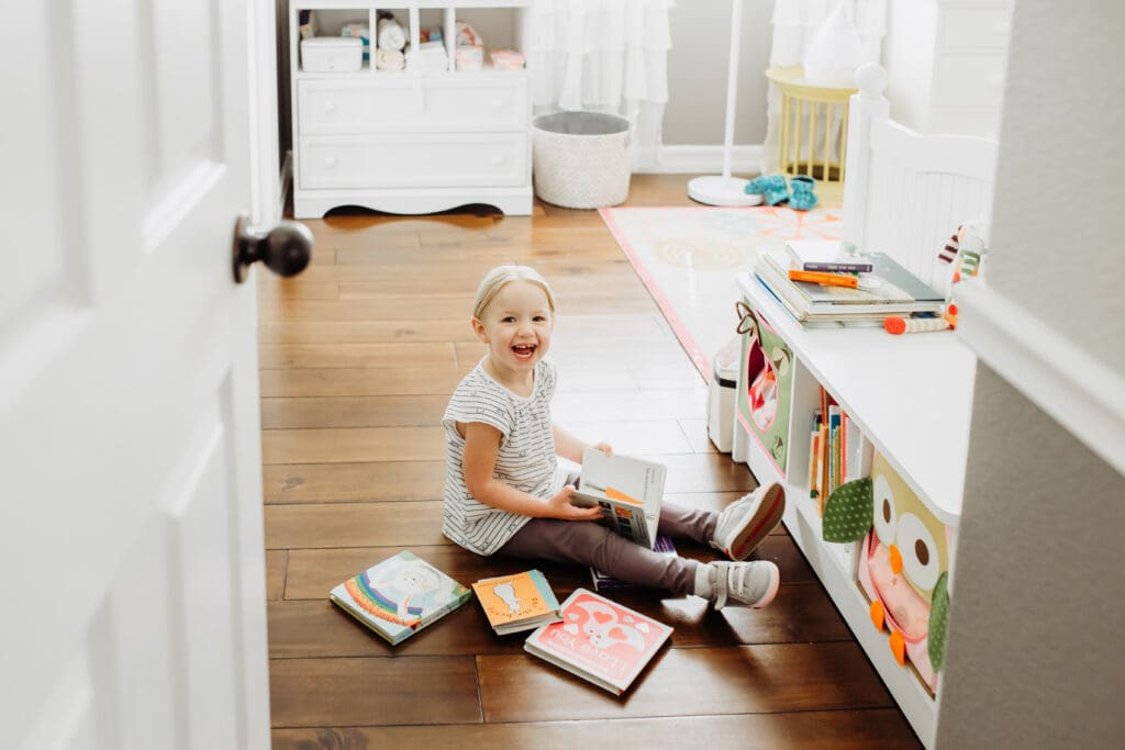 toddler girl sits on the floor of her room for a blog post about in-home lifestyle photo session