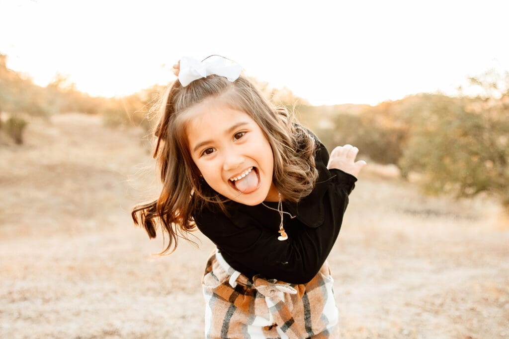 backlit image of a Little girl being silly in a blog post about how to prepare kids for a photo session