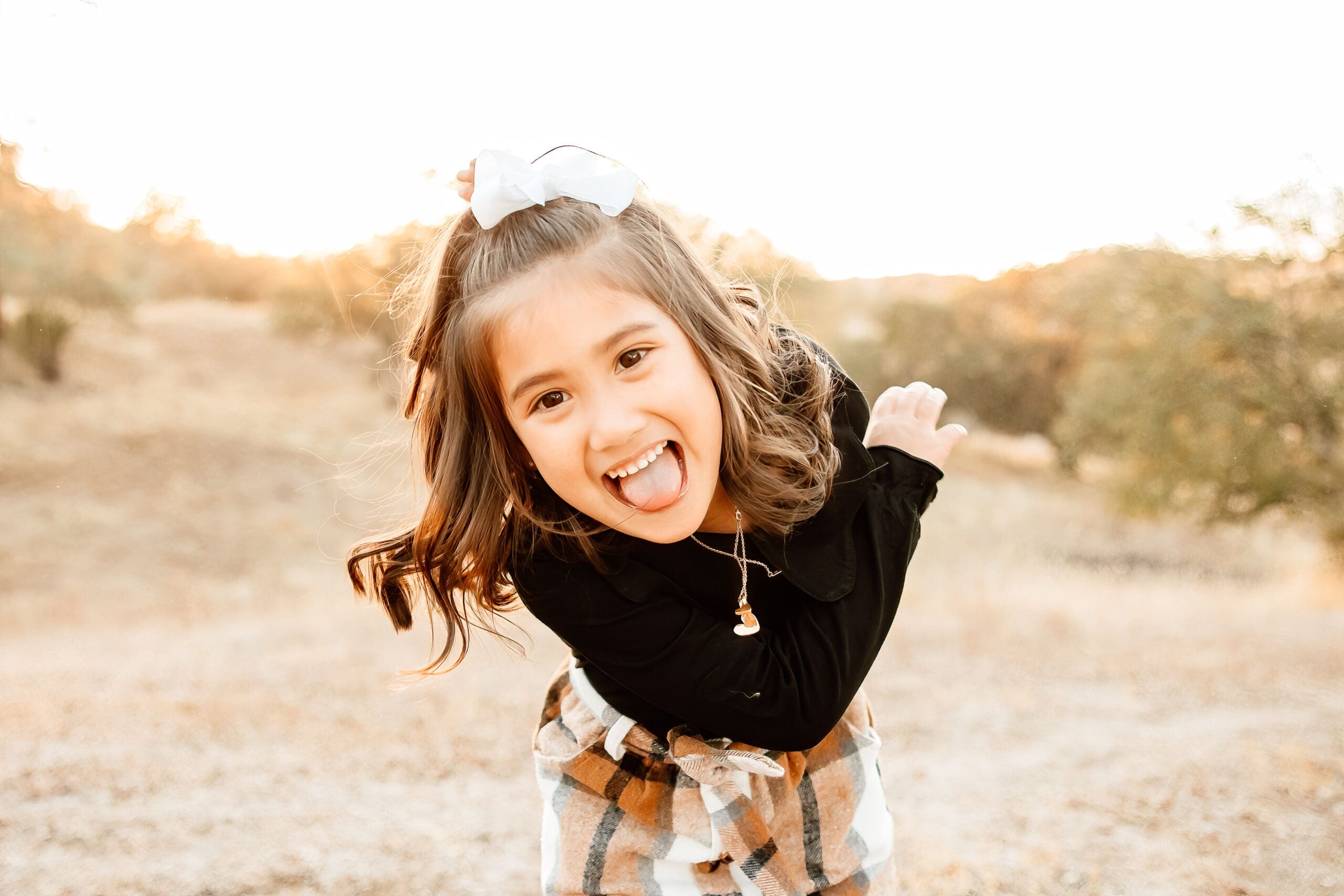Backlit image of a little girl being silly during a family photo session with Sweet Whimsy Photography