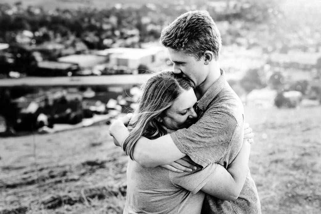 black and white portrait of a senior boy hugging his mom